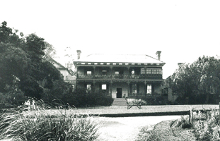 House with trees either side and garden in front