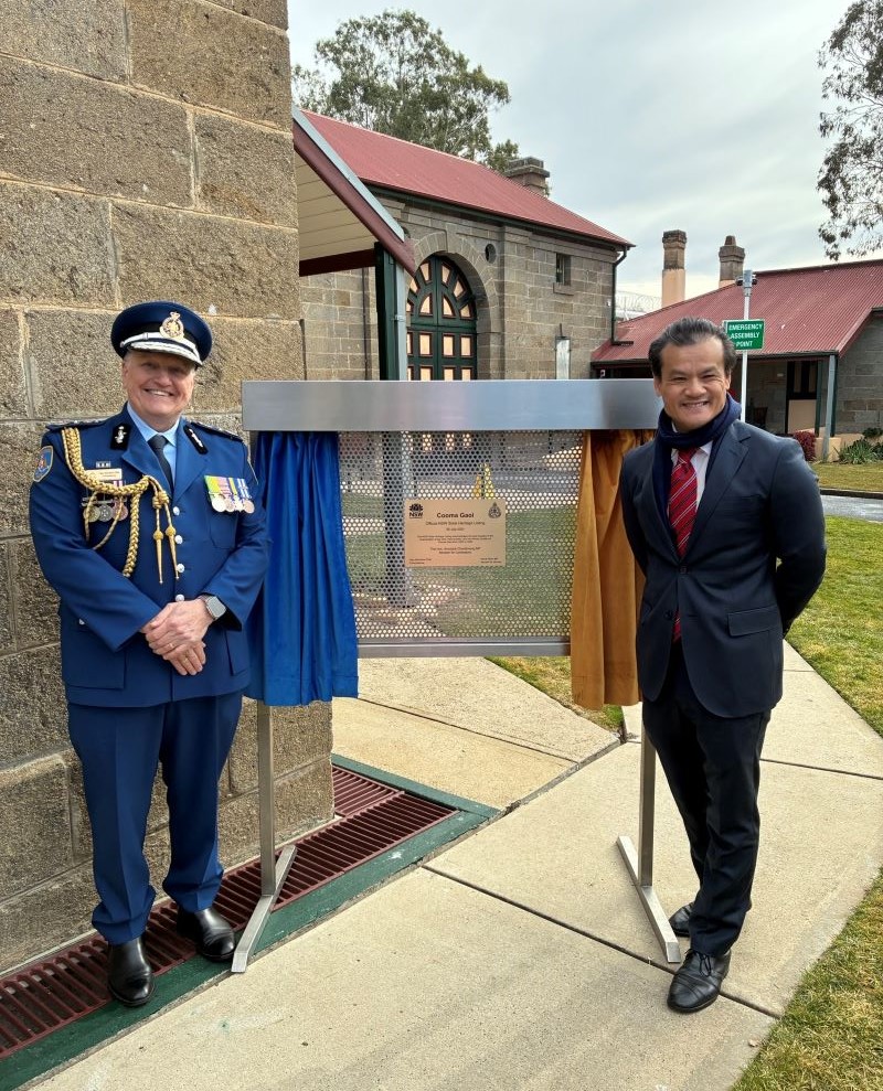 Commissioner Gary McMahon and Minister Anoulack Chanthivong stand next to the new building plaque