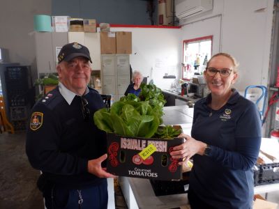 Male correctional officer hands a box of vegetables to woman inside the shop 