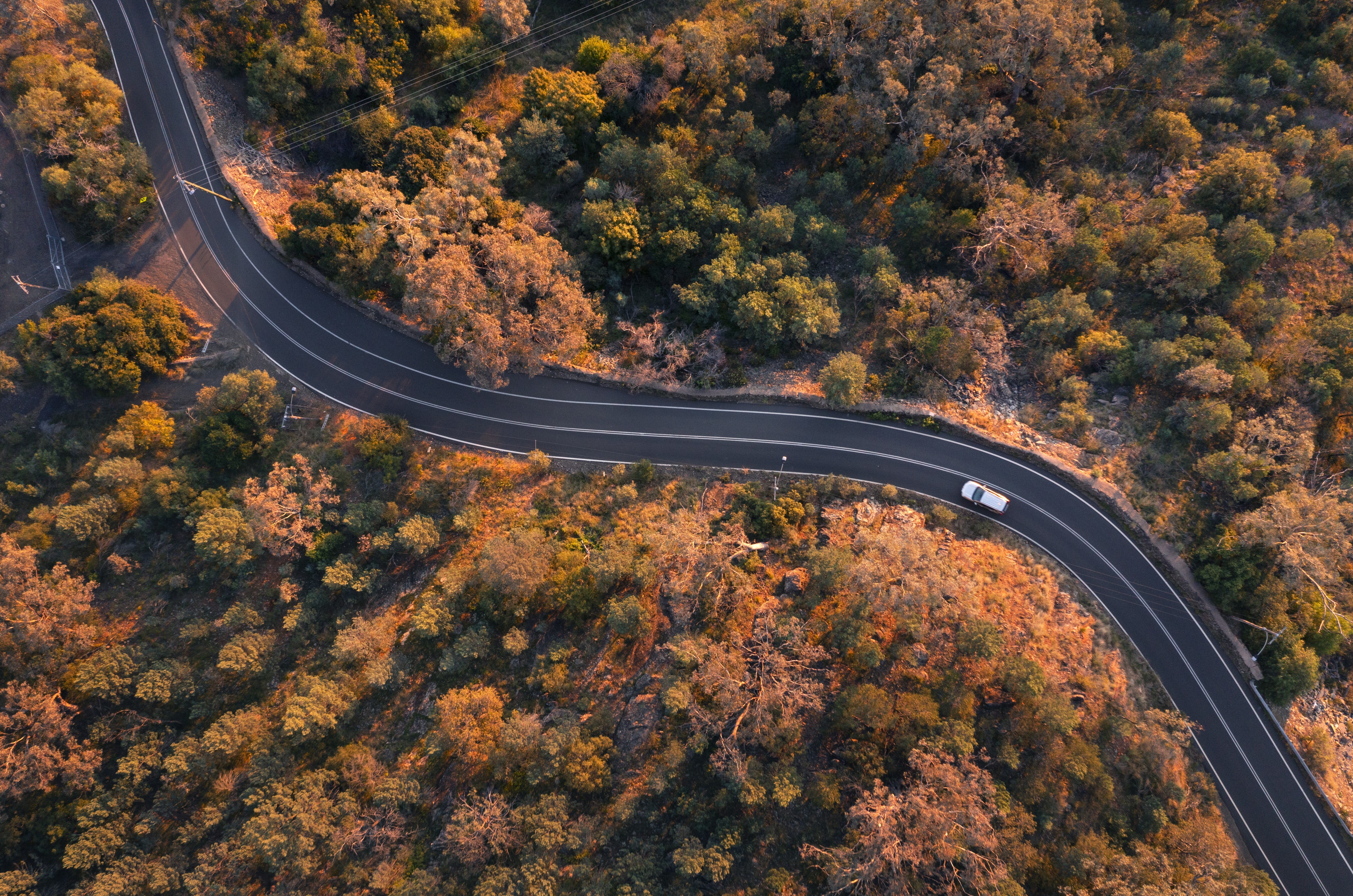 An aerial photo of a car driving on a country road in Tamworth at golden hour