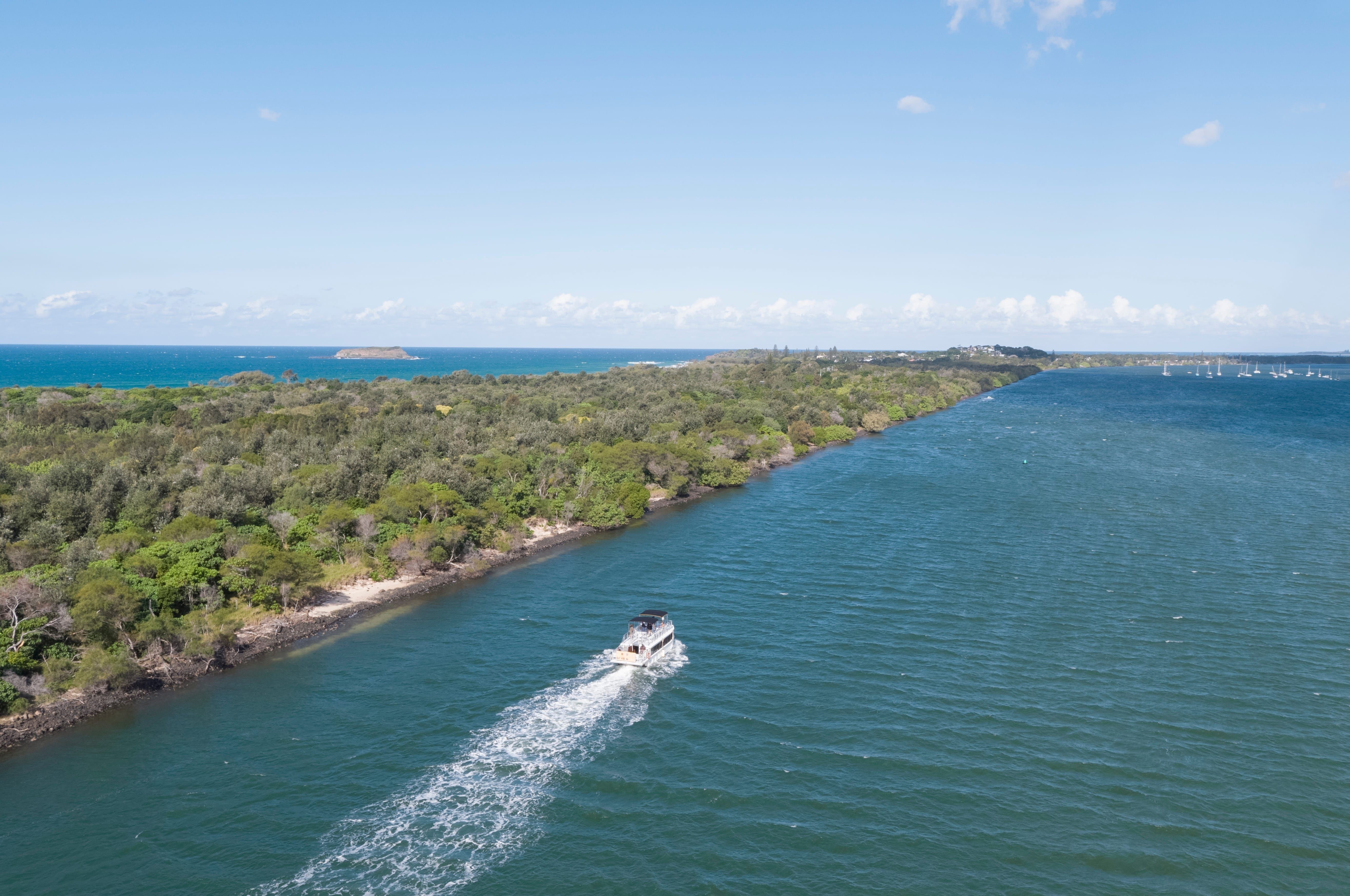 An aerial photo of the Tweed River with a boat travelling down it