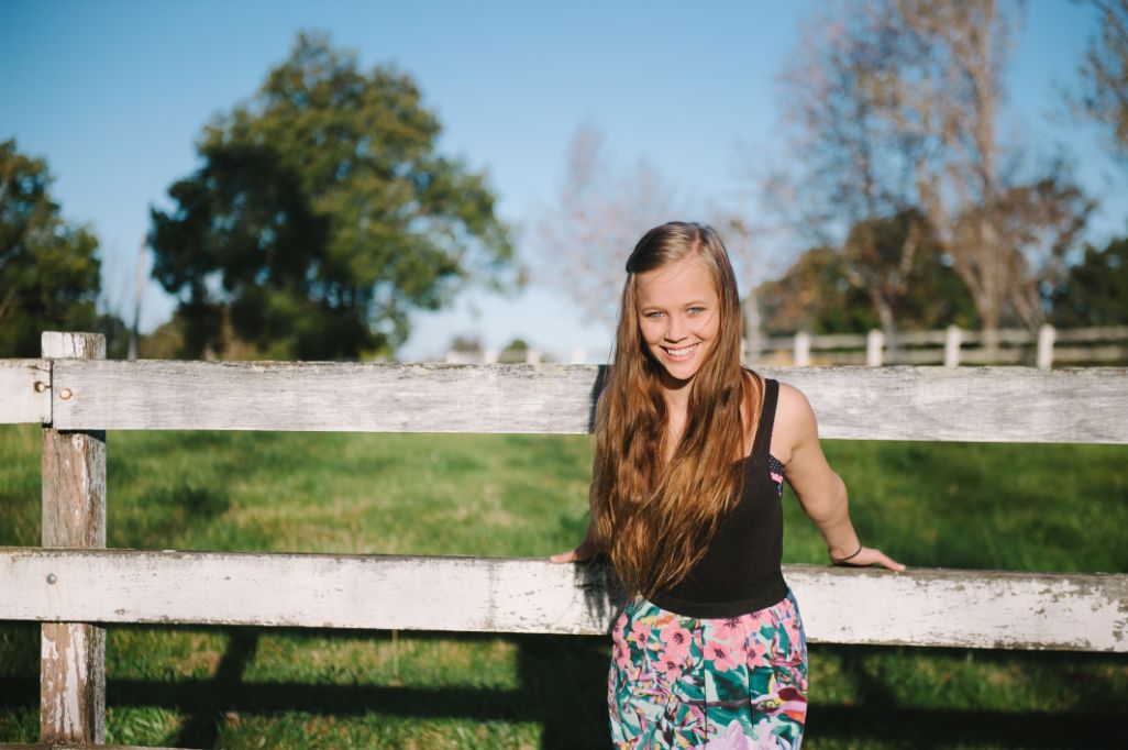 Carrie on a fence smiling happily