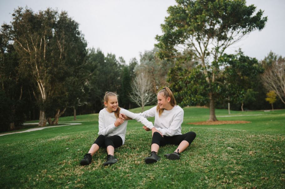 A picture of Madeline and Jessica sitting on some grass playing 