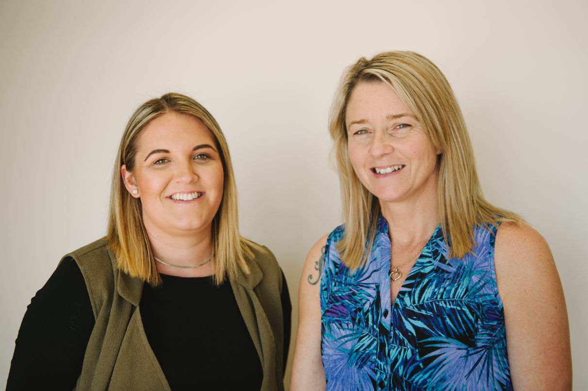 Two adult females standing next to each other smiling 