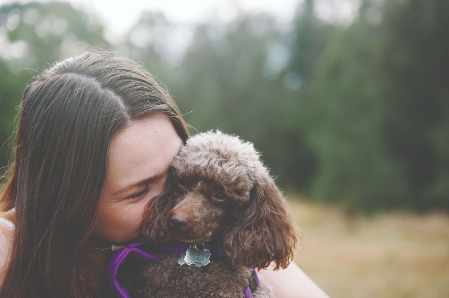 Selina kissing a small brown dog