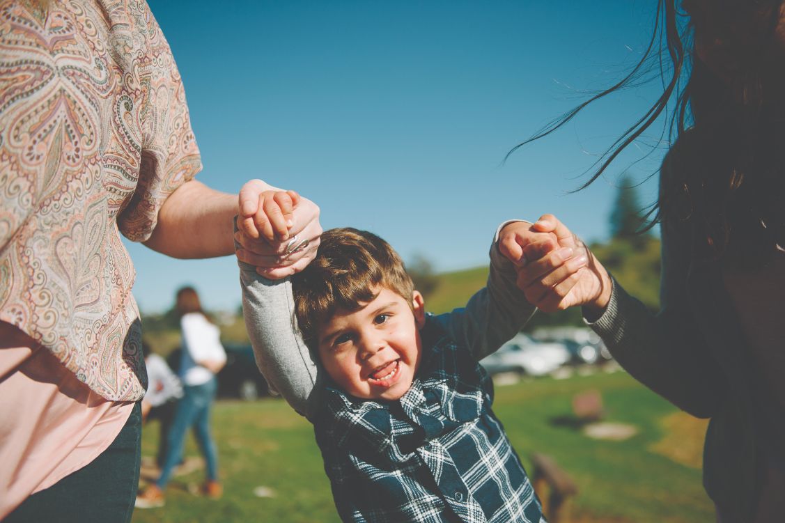 A picture of Mason having fun and holding hands with two people