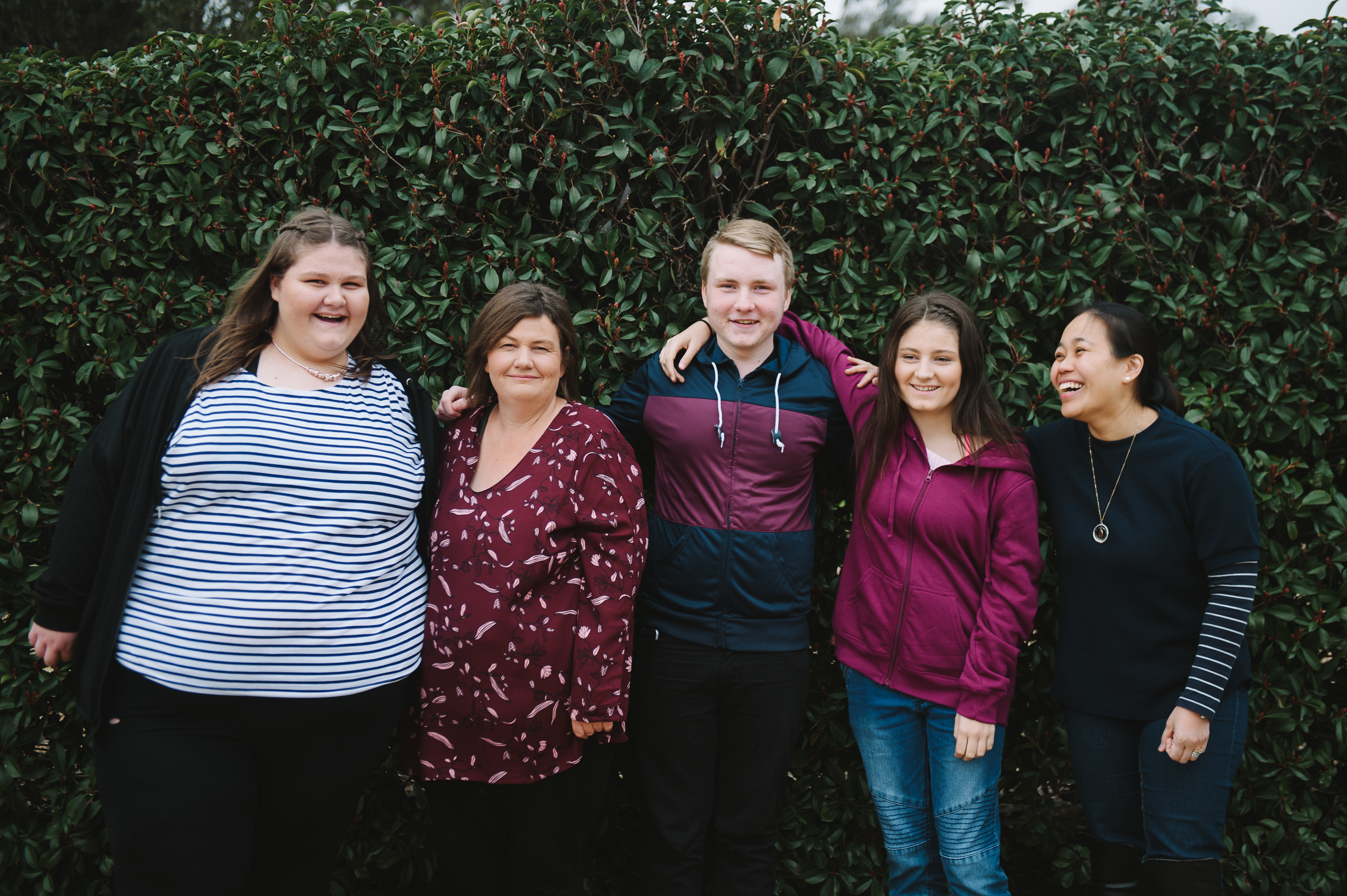 Five adults standing together smiling and happy