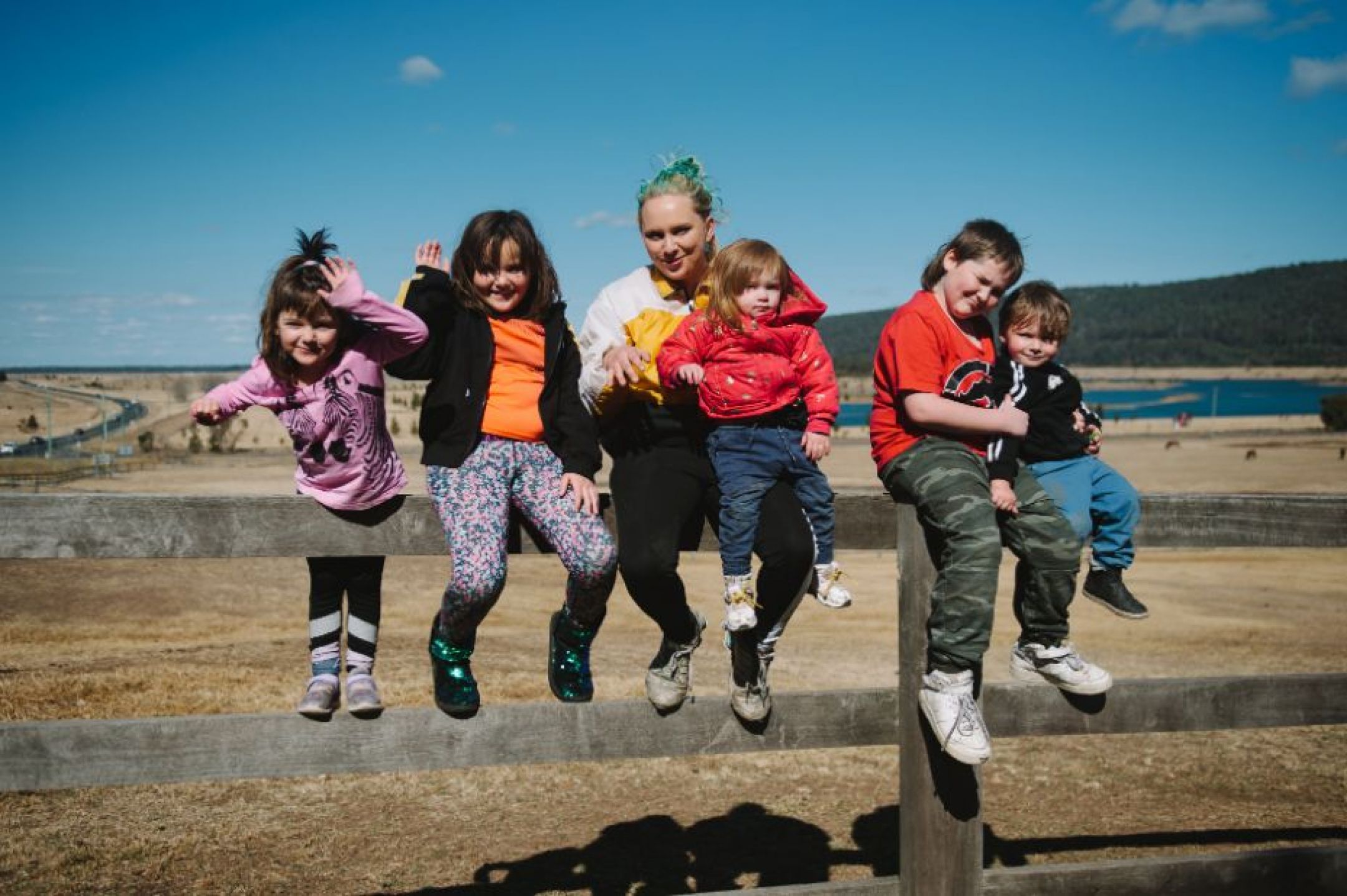 Sarah and her children sitting on a wooden fence