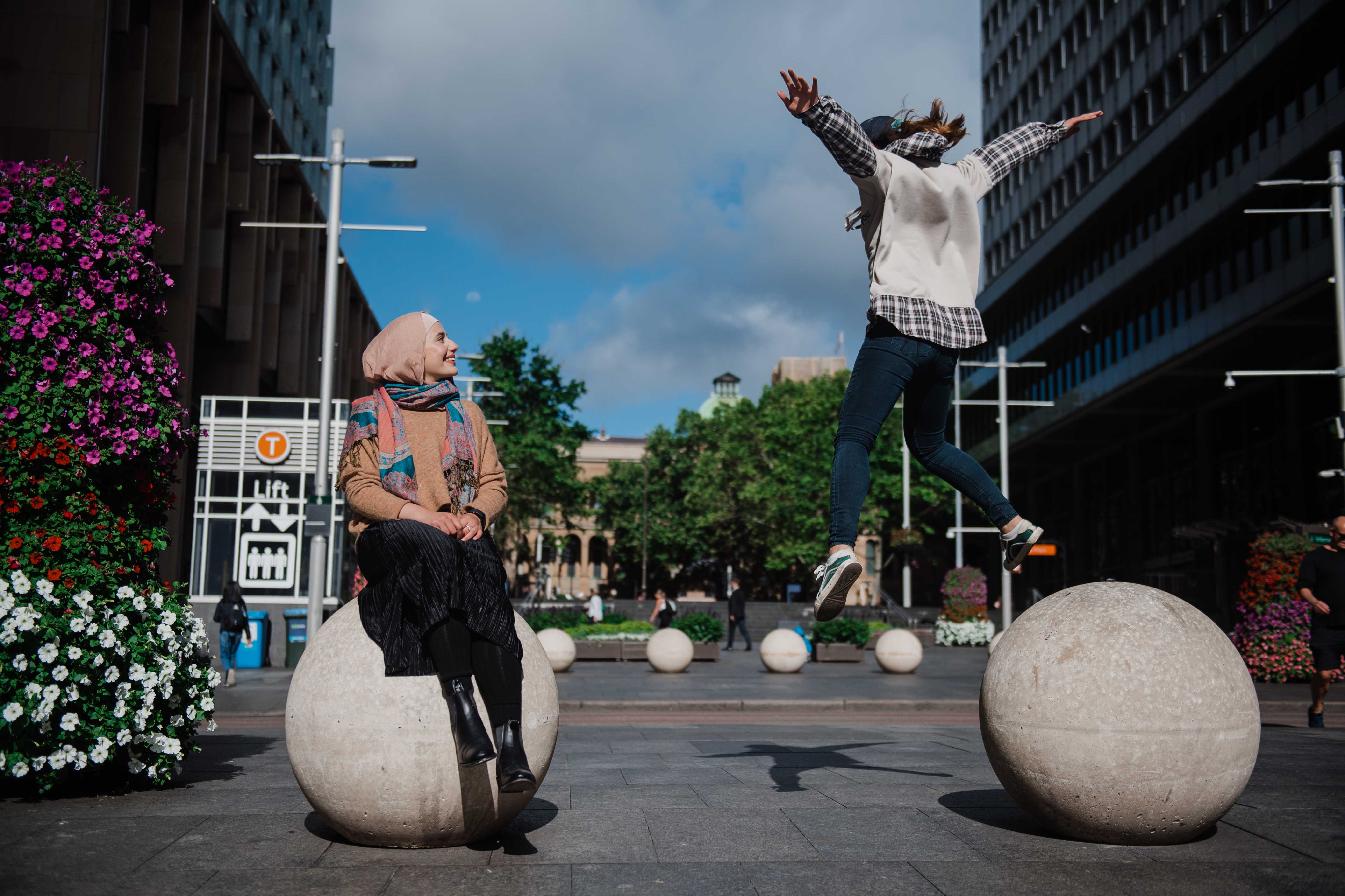 Hope jumping off a concrete sculpture with Sarah sitting on another looking on